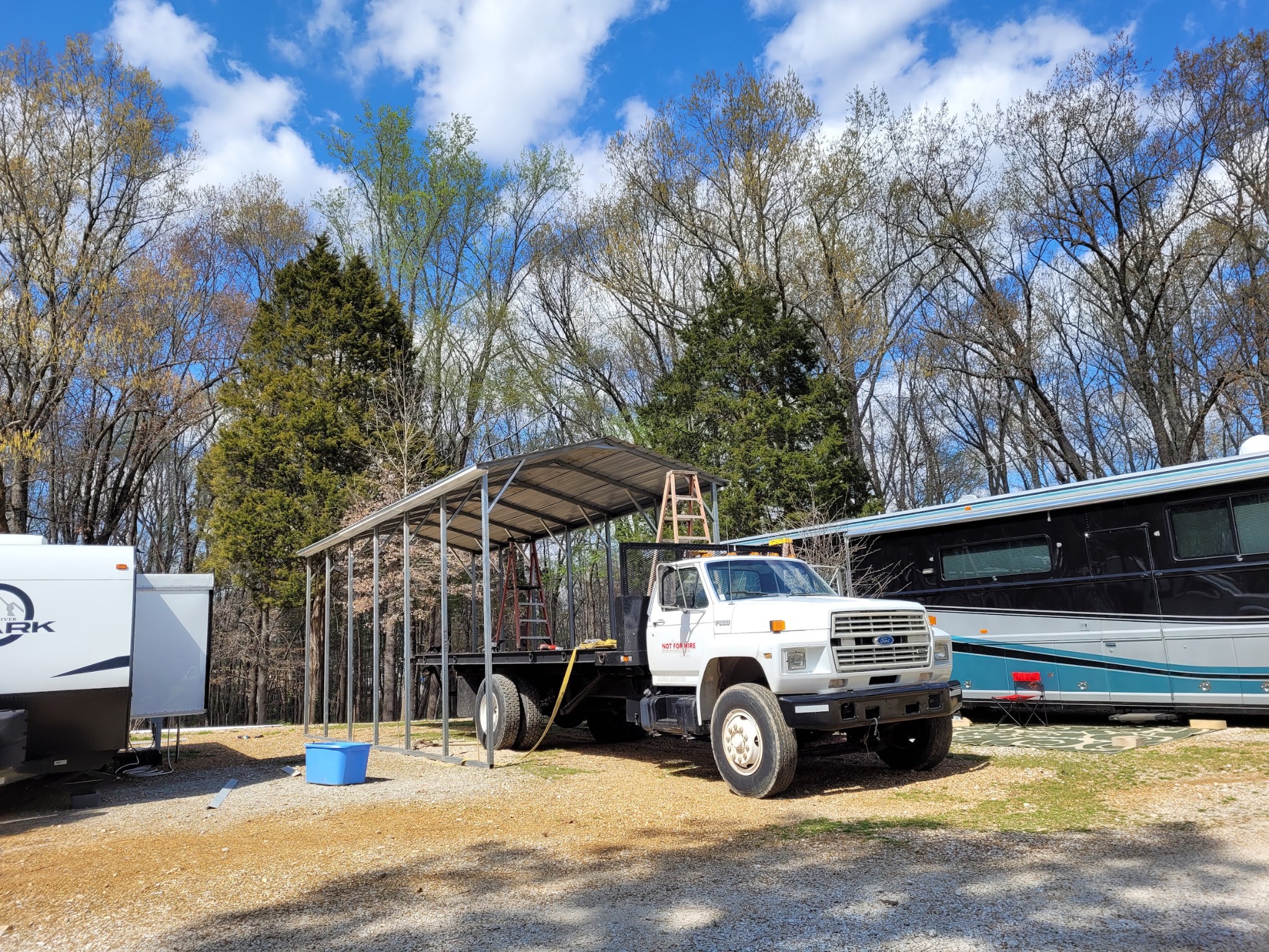 Metal carport frame beside an RV and truck